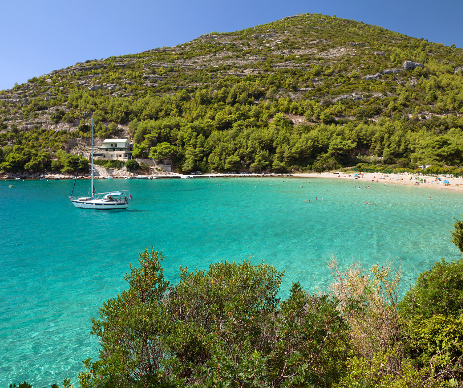 Bucht mit kristallklarem Wasser und einem Segelboot