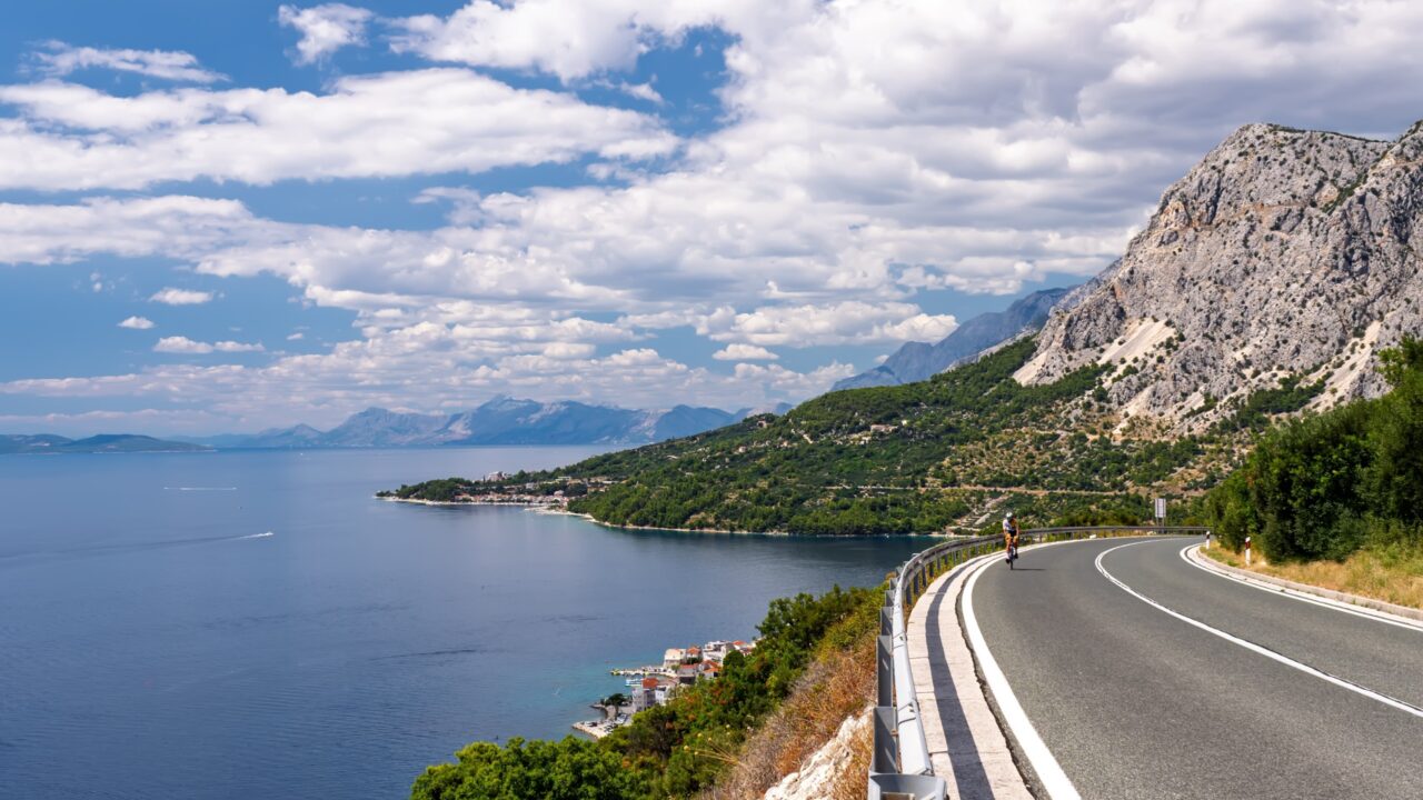 Ein Radfahrer genießt eine Fahrt auf der spektakulären Adriaküstenstraße entlang der bergigen Küste der Makarska-Riviera in Kroatien. Atemberaubende Sommerlandschaft der dalmatinischen Küste.